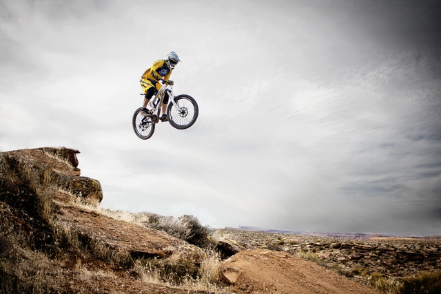 Man jumping high and across desert with bicycel