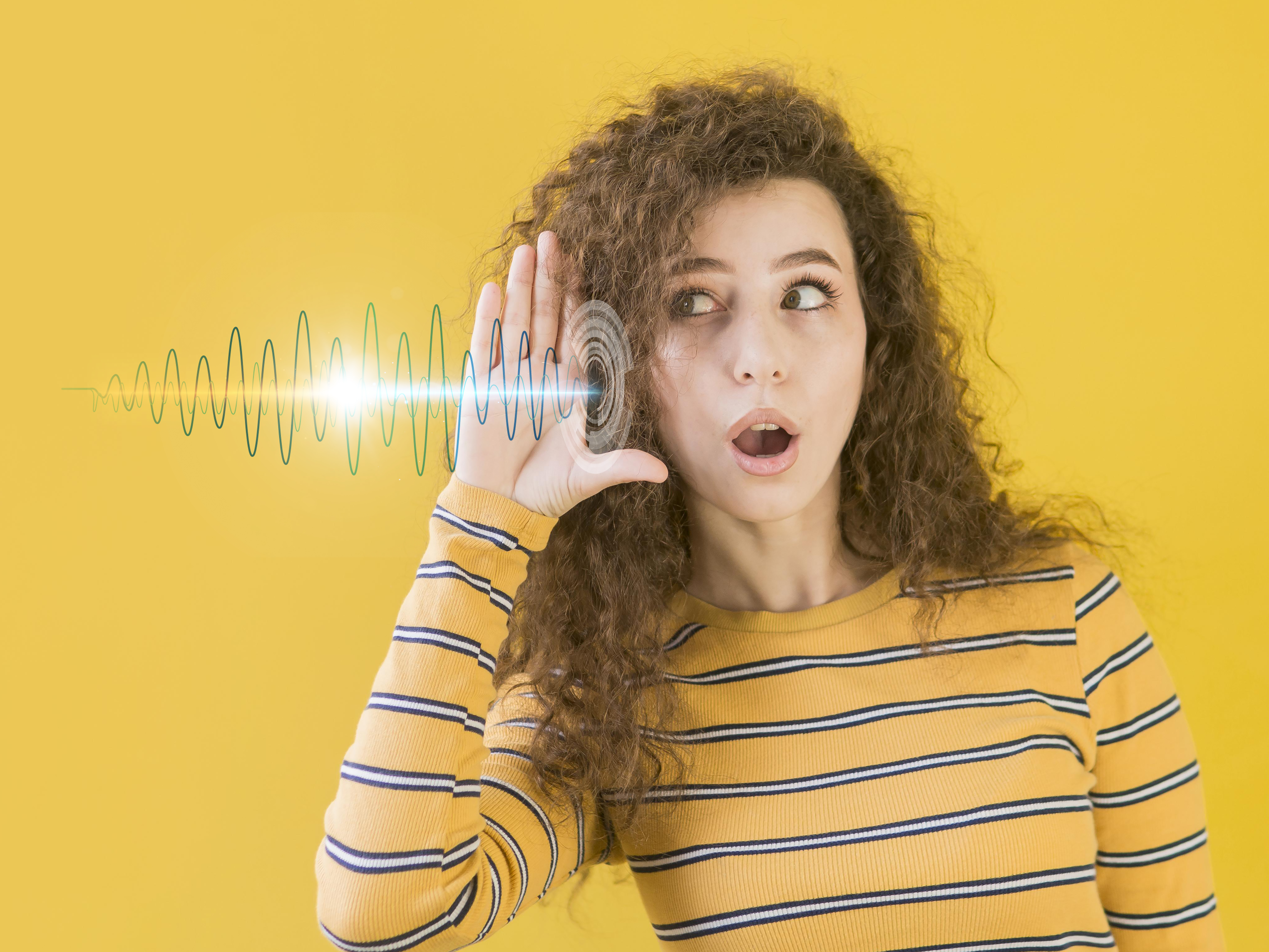 Woman with a hand next to her ear, listening to a sound wave, representing the challenge of how to evaluate customer feature requests.