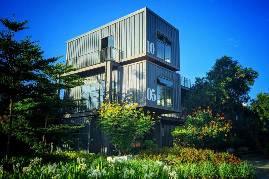 Modular container houses arranged on green grass surrounded by trees, illustrating the concept of scalable and interchangeable product architecture.